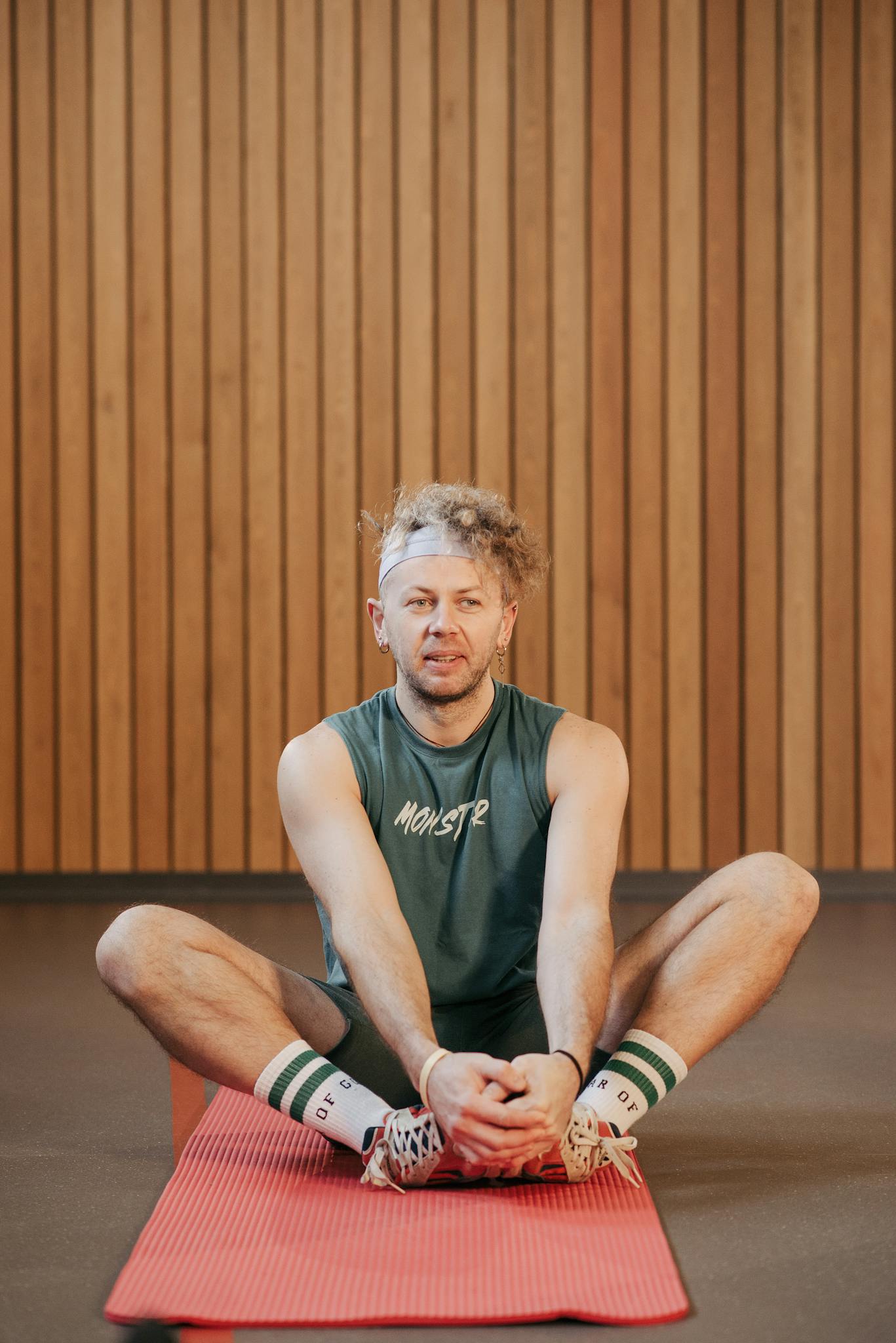 Adult man in sportswear stretching indoors on a yoga mat, focusing on preparation.