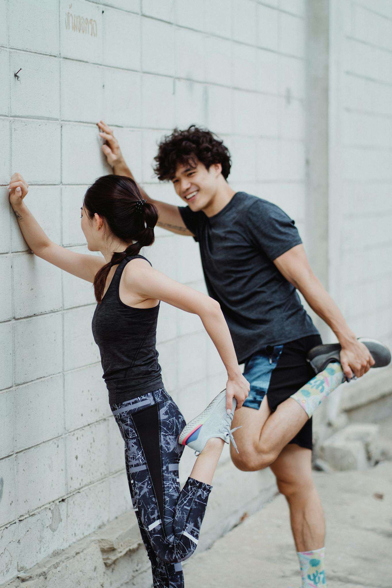 Energetic young couple stretching against a wall, embracing a healthy lifestyle.